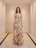 Woman wearing a cream floral print maxi dress with spaghetti straps and a high slit.