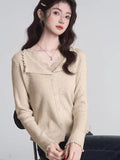 A woman models a grey ribbed knit cropped tank top with lace trim and a bow, styled with white pants.