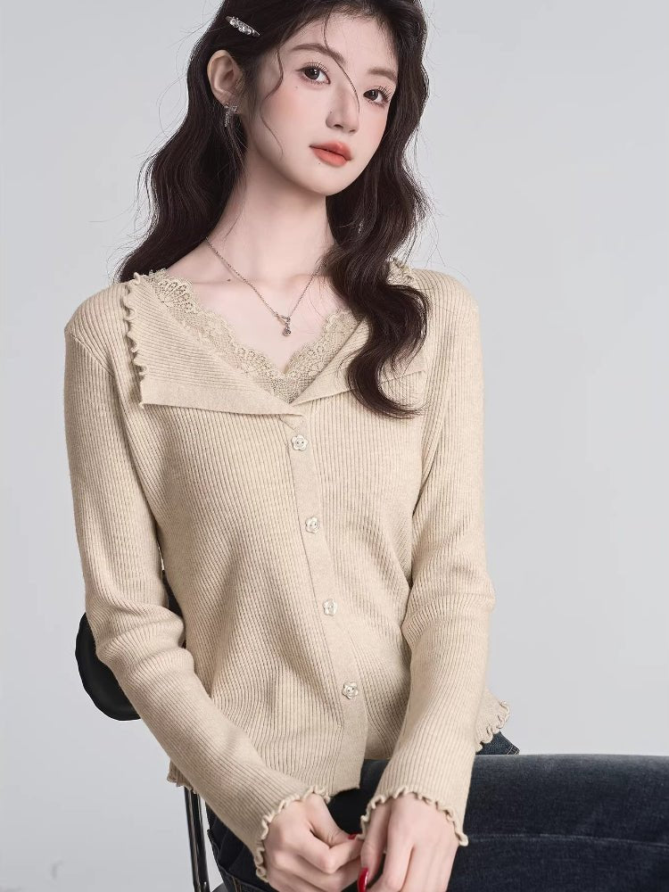 A woman models a grey ribbed knit cropped tank top with lace trim and a bow, styled with white pants.