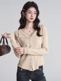 Woman wearing a grey ribbed knit cropped tank top with lace trim and a small bow detail on the square neckline.