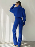 Back view of a woman in a royal blue knit set, showing the relaxed fit of the top and the straight leg of the pants.