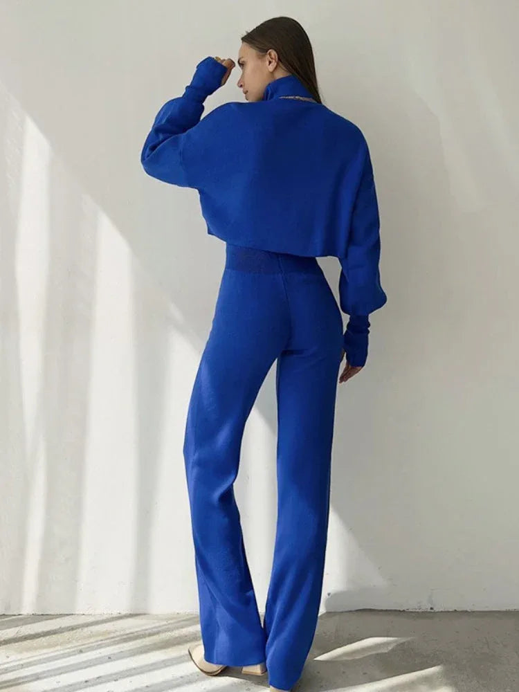 Back view of a woman in a royal blue knit set, showing the relaxed fit of the top and the straight leg of the pants.