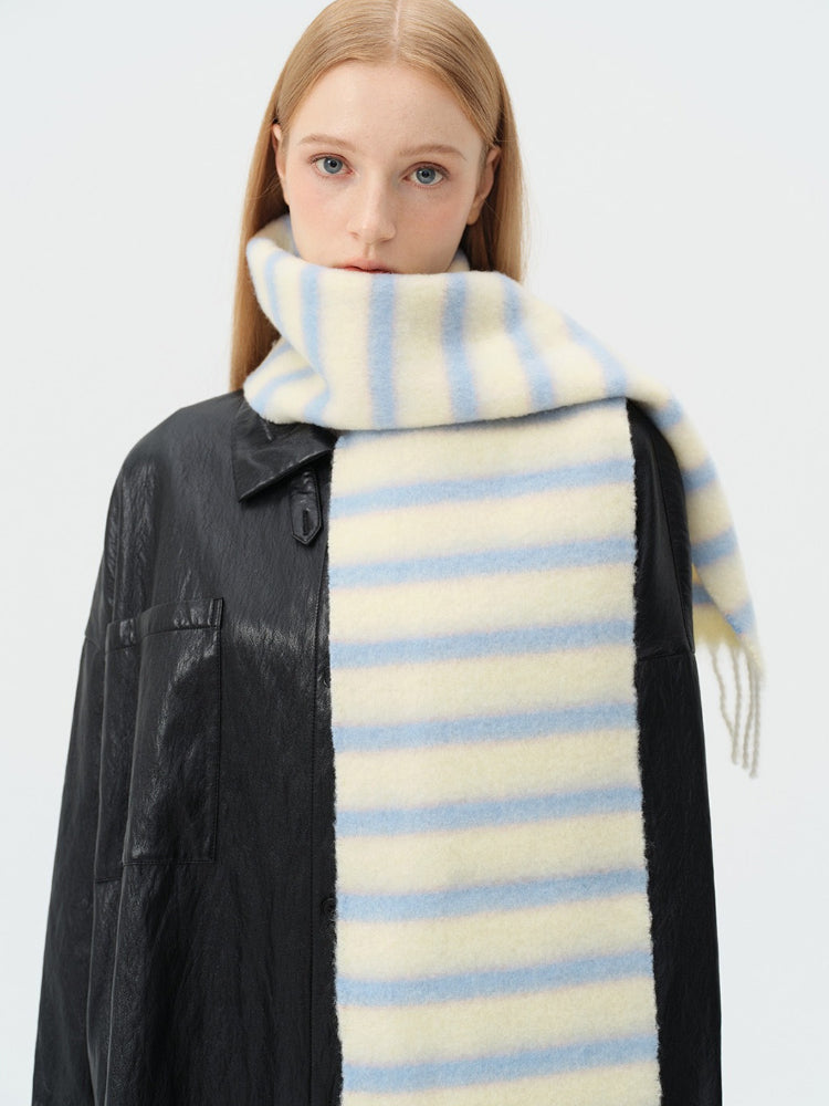 Portrait of a woman with a cream and light blue striped scarf wrapped around her neck.