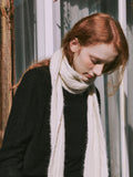 Close-up of a woman's face and neck, with a cream scarf draped around her.