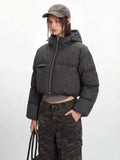 Model showcasing a cropped grey puffer jacket with a hood and silver zipper details.