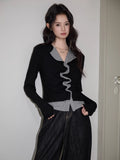 Front view of a woman in a black and grey layered top with ruched detailing.