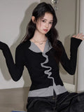 Woman in a black and grey layered top with ruched front, gesturing with hands.
