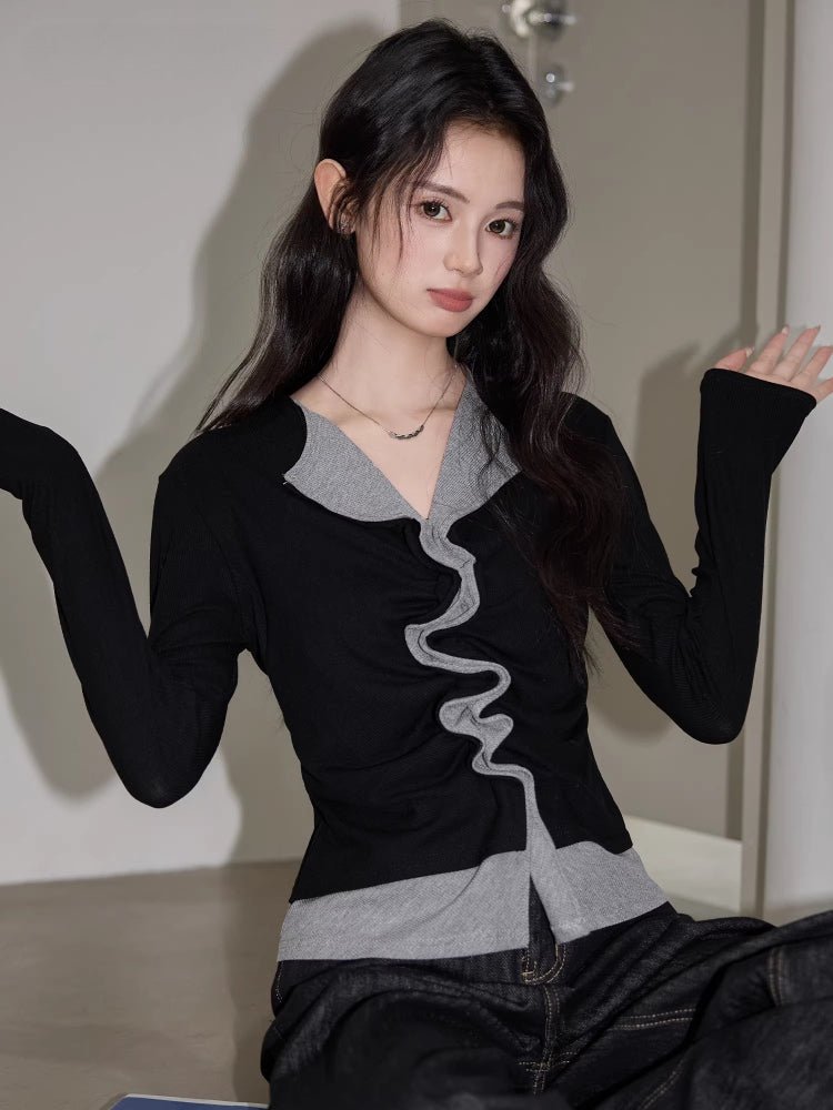 Woman in a black and grey layered top with ruched front, gesturing with hands.