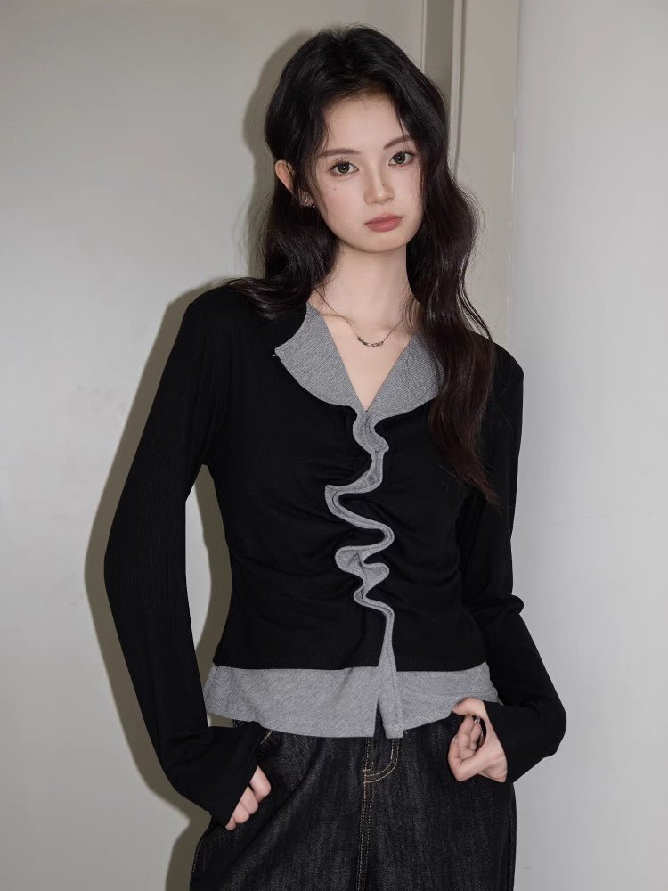 Woman wearing a black long-sleeve top with a grey layered neckline and ruched front detail.