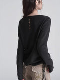 Rear view of a woman wearing a dark grey knit sweater with button detail on the back.