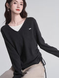 Close-up of a woman wearing a dark grey v-neck knit sweater with ruched sides.