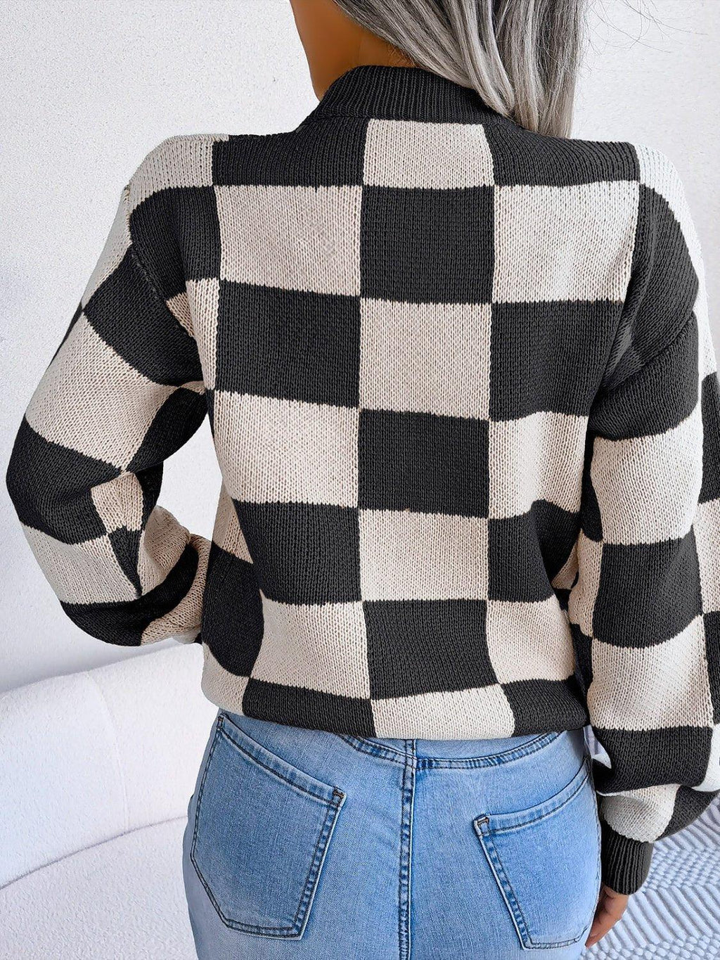 Back view of a woman wearing a black and cream checkerboard knit sweater.