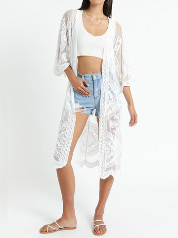Woman wearing a white lace kimono over a white crop top and denim shorts