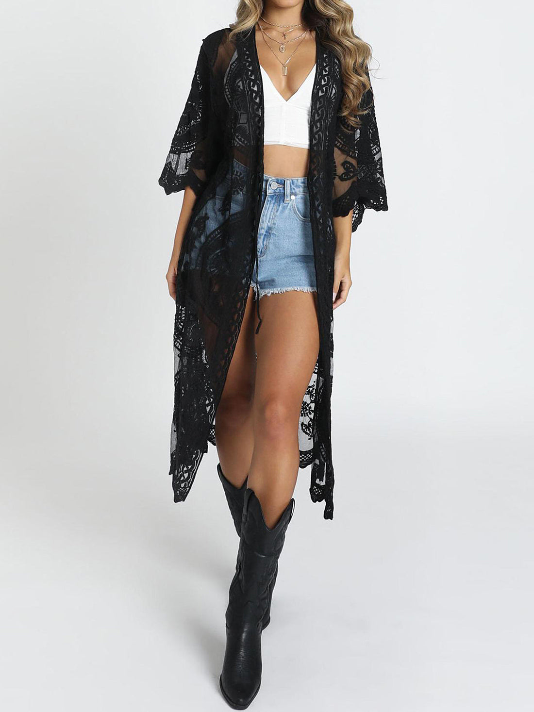 Woman wearing a white lace kimono over a white crop top and denim shorts
