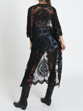 Back view of a woman wearing a black lace kimono over a white crop top and denim shorts