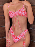 Woman wearing a pink floral print bikini with ruched top and adjustable ties