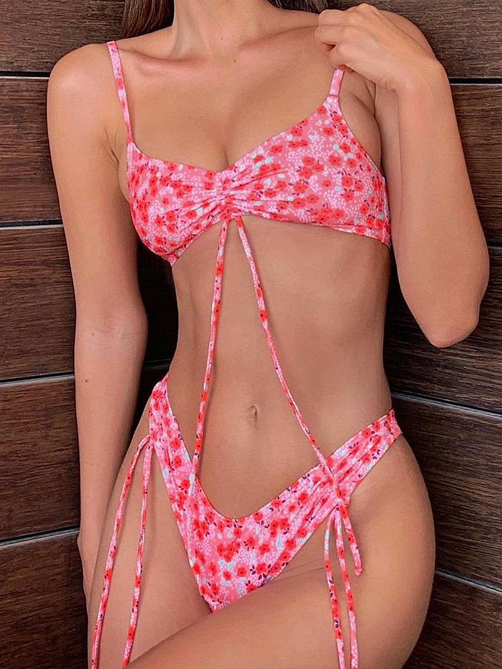 Woman wearing a pink floral print bikini with ruched top and adjustable ties