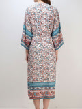 Back view of a woman wearing a long, floral print kimono with wide sleeves.