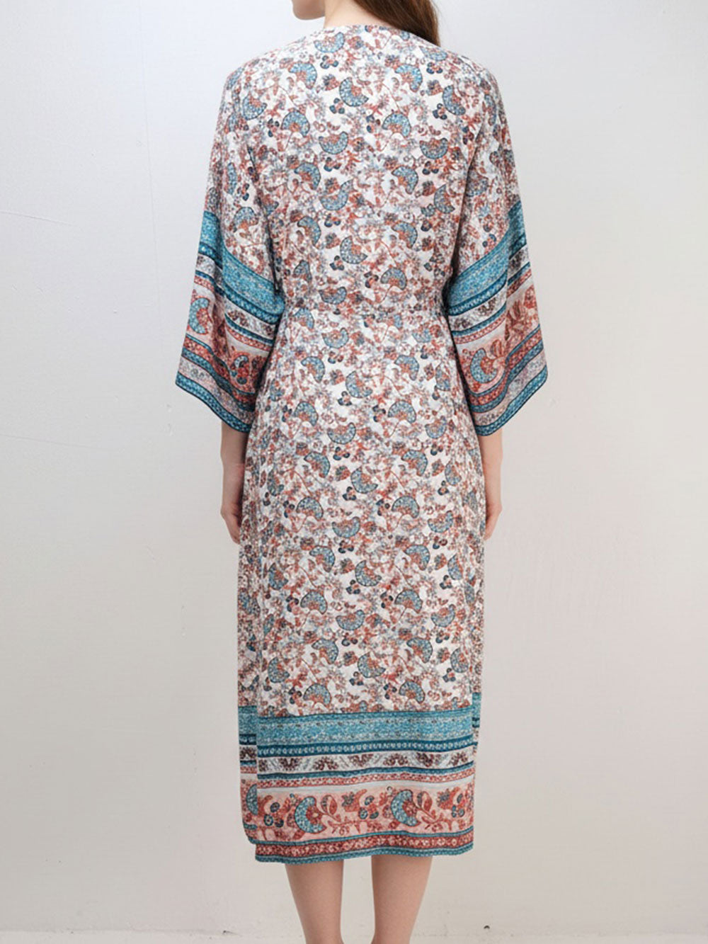 Back view of a woman wearing a long, floral print kimono with wide sleeves.