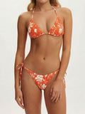 Woman wearing an orange and white floral print bikini with halter top and tie-side bottoms