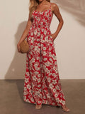 Woman wearing a red floral print wide-leg jumpsuit with a smocked bodice and spaghetti straps.