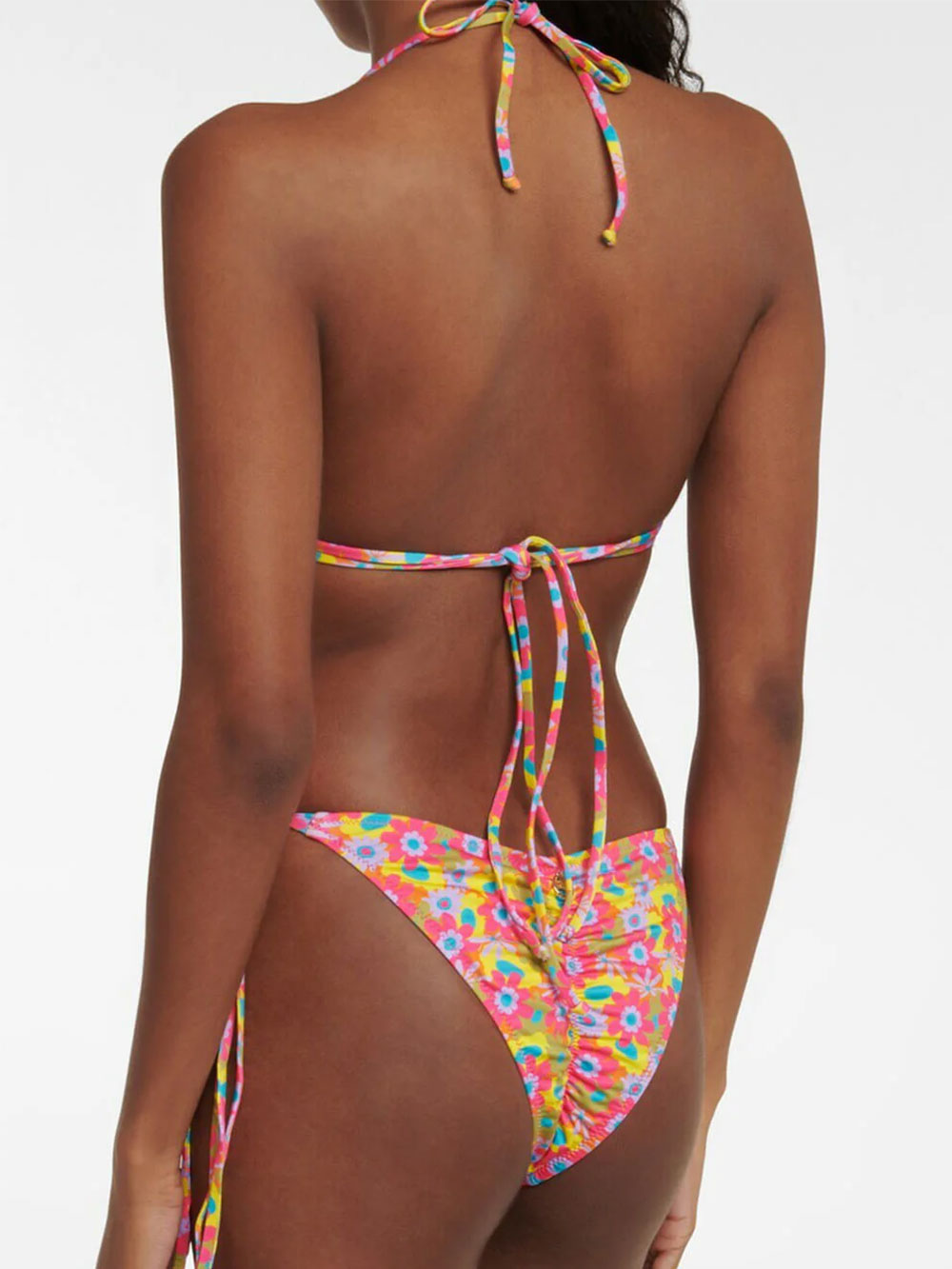Woman wearing the back of a floral print bikini set with adjustable ties on the top and ruched detail on the bottoms