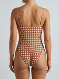 Rear view of a woman wearing a brown and beige geometric print one-piece swimsuit.