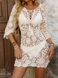 Woman wearing a white crochet knit mini dress with 3/4 sleeves and a tassel tie neckline.