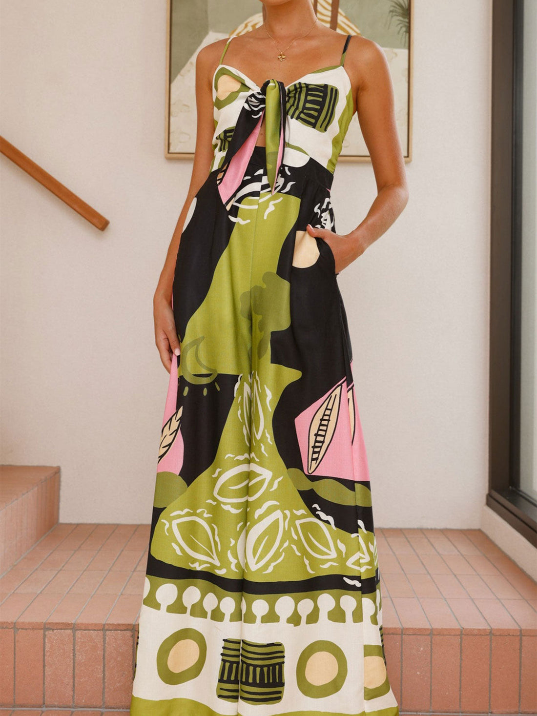 Woman wearing a colorful printed wide-leg jumpsuit with a tie-front detail and cut-out.