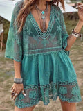 Woman wearing a teal lace cover-up with a V-neck and embroidered details.
