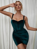 Woman in a dark green velvet ruched bodycon dress with a sweetheart neckline and dark straps.