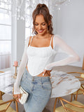 Woman smiling and posing in a white ruched bust corset top with sheer long sleeves