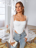 Woman wearing a white ruched bust corset top with sheer long sleeves and blue denim jeans