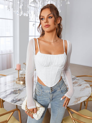 Woman wearing a white ruched bust corset top with sheer long sleeves and blue denim jeans