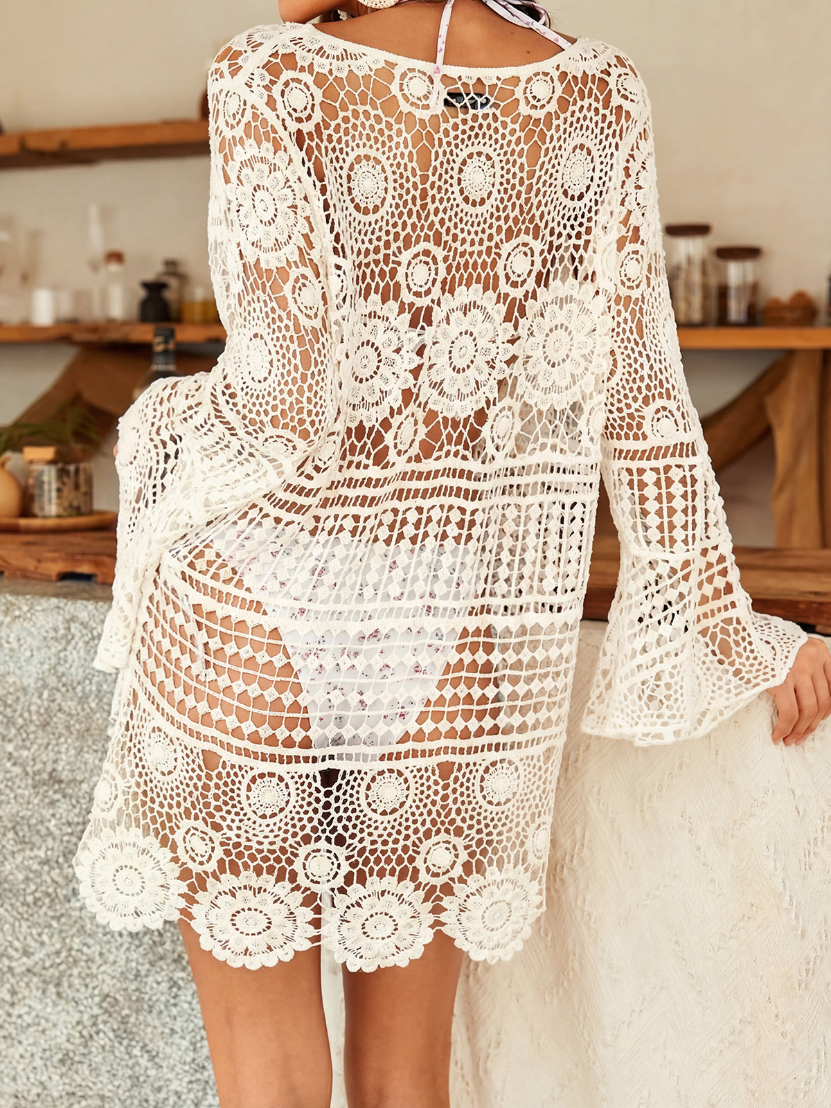 Woman wearing a black crochet knit beach cover-up with lace-up neckline and bell sleeves