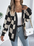 Woman wearing a black and cream checkerboard knit cardigan, white tank top, blue jeans, and gold jewelry.