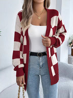 Woman in a red and cream checkerboard knit cardigan with a white tank top and blue jeans.