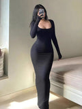 Woman in a long-sleeved, fitted black dress with a high slit and embellishment, posing against a metallic background.