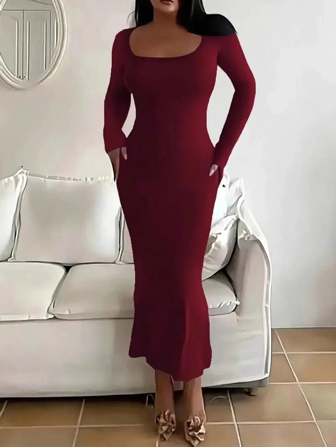 Woman in a long-sleeved, form-fitting, scoop neck red maxi dress.