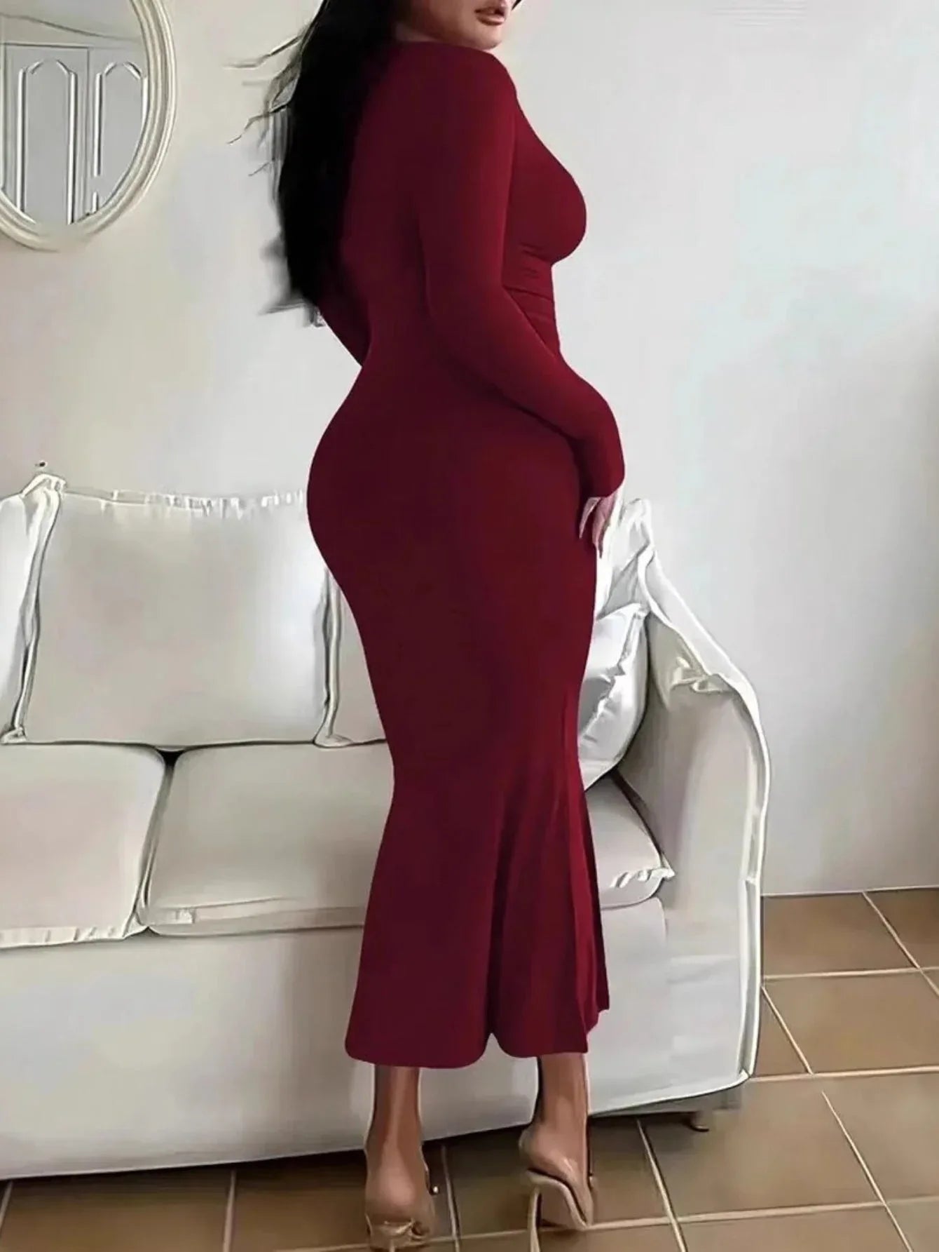 Rear view of a woman in a long-sleeved, form-fitting, scoop neck red maxi dress.