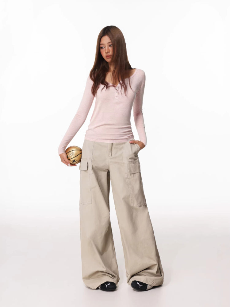 Woman holding a basketball, wearing a pink long-sleeve henley shirt and beige wide-leg cargo pants