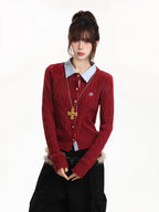 Front view of a woman in a red cable knit cardigan, blue collared shirt, and black cargo pants.