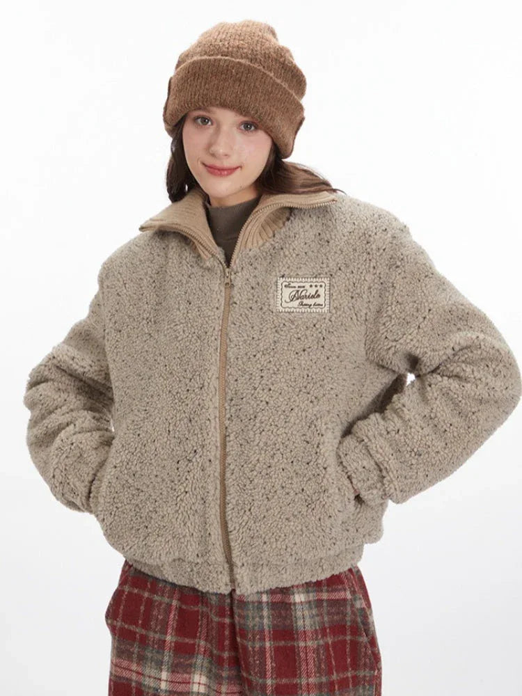 Front view of a model wearing a tan fleece bomber jacket with hands in pockets.