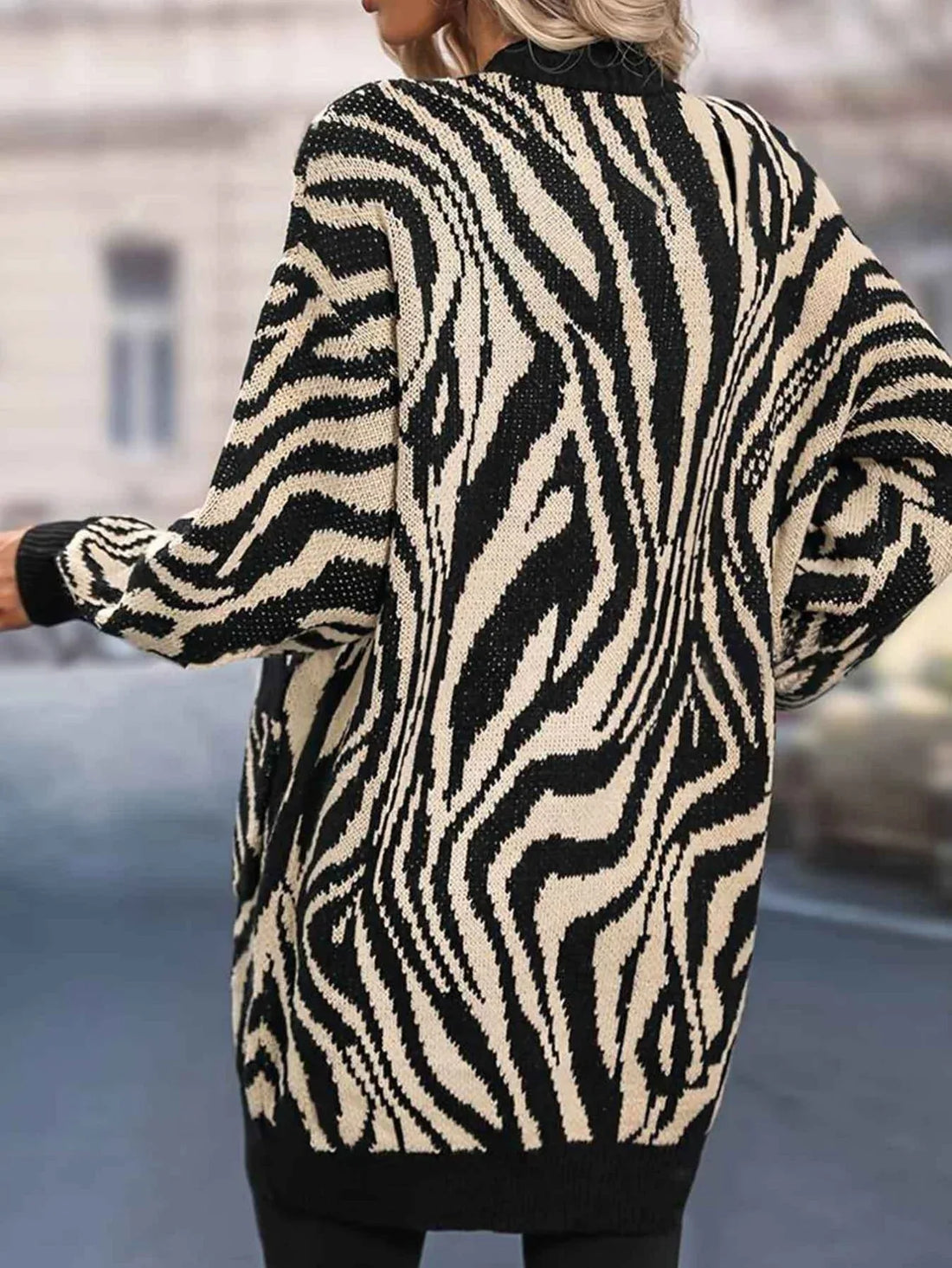 Woman wearing a black and white zebra print long cardigan with pockets and balloon sleeves.