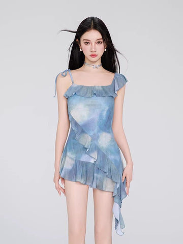 Woman wearing a blue tie-dye print mini dress with ruffle trim and tie shoulder straps