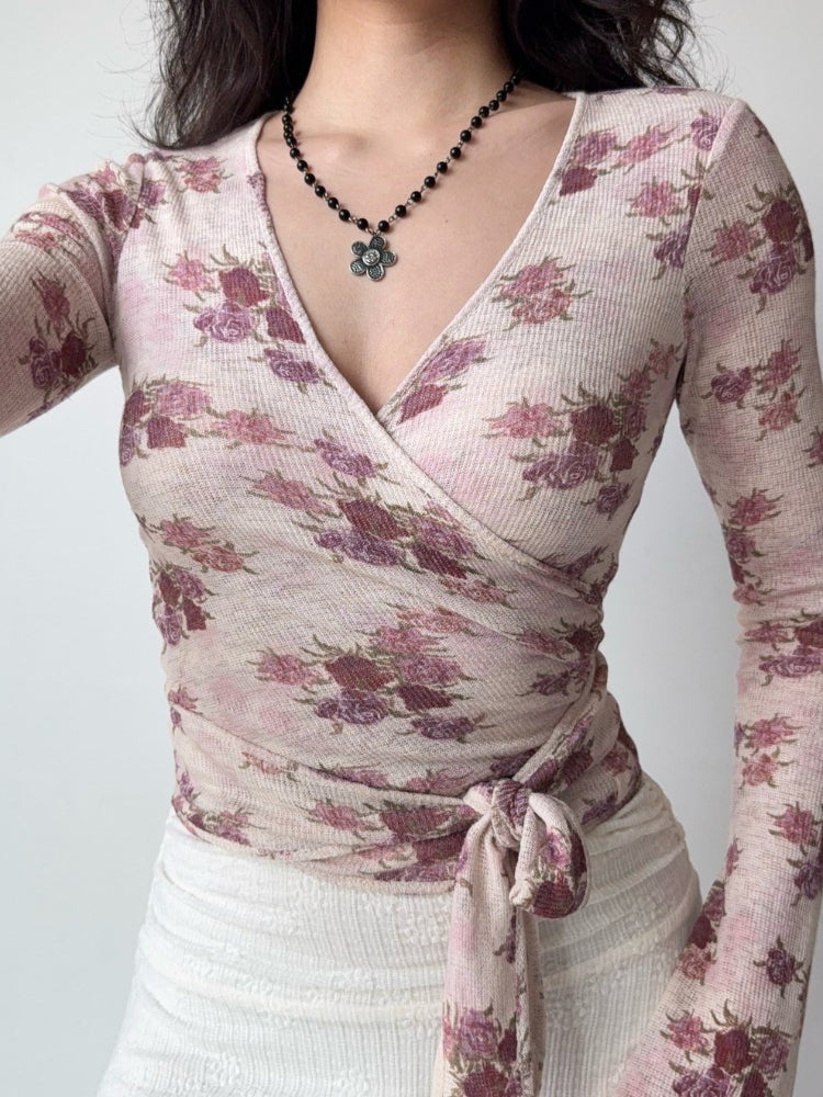 Close-up of a woman's torso showing the v-neckline and tie detail of a floral print wrap top.