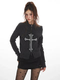 Front view of a woman in a dark grey knit zip-up cardigan with a prominent cross design.