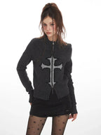 Front view of a woman in a dark grey knit zip-up cardigan with a prominent cross design.