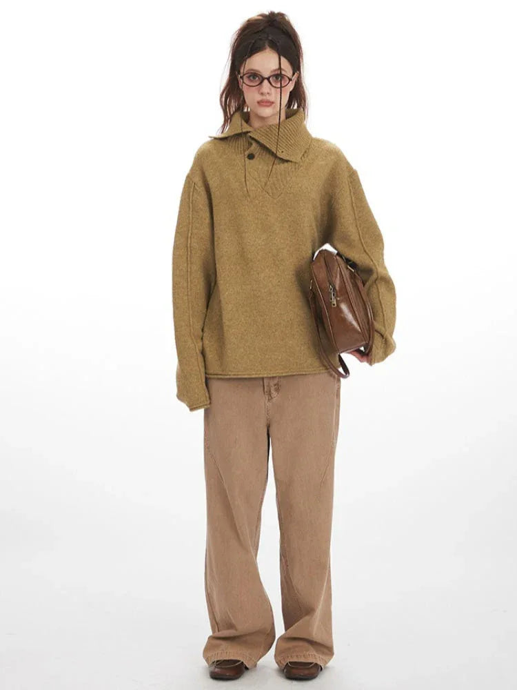 Woman wearing an oversized camel knit sweater with a collared V-neck and button closure, paired with brown wide-leg jeans and holding a brown crossbody bag.