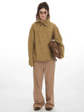 Woman wearing an oversized camel knit sweater with a collared V-neck and button closure, paired with brown wide-leg jeans and holding a brown crossbody bag.